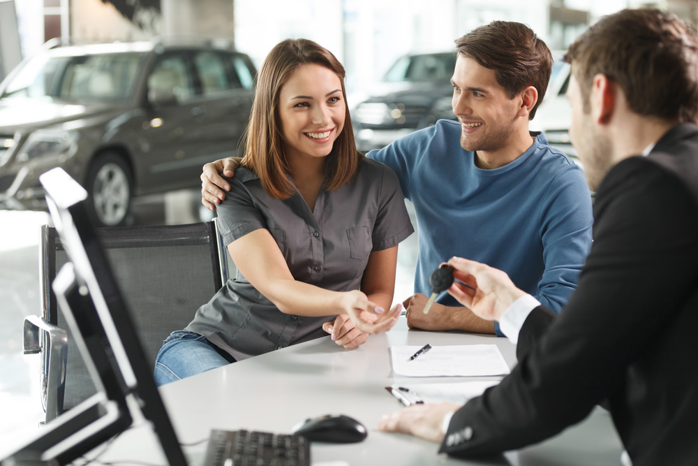 couple at desk at a car dealership