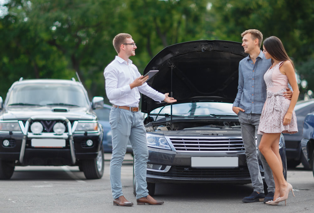 couple in car lot with used car dealer