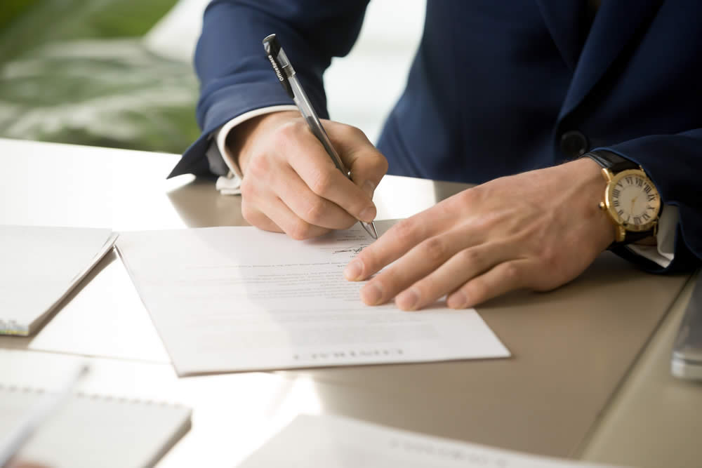 Man signing documents on desk in his office