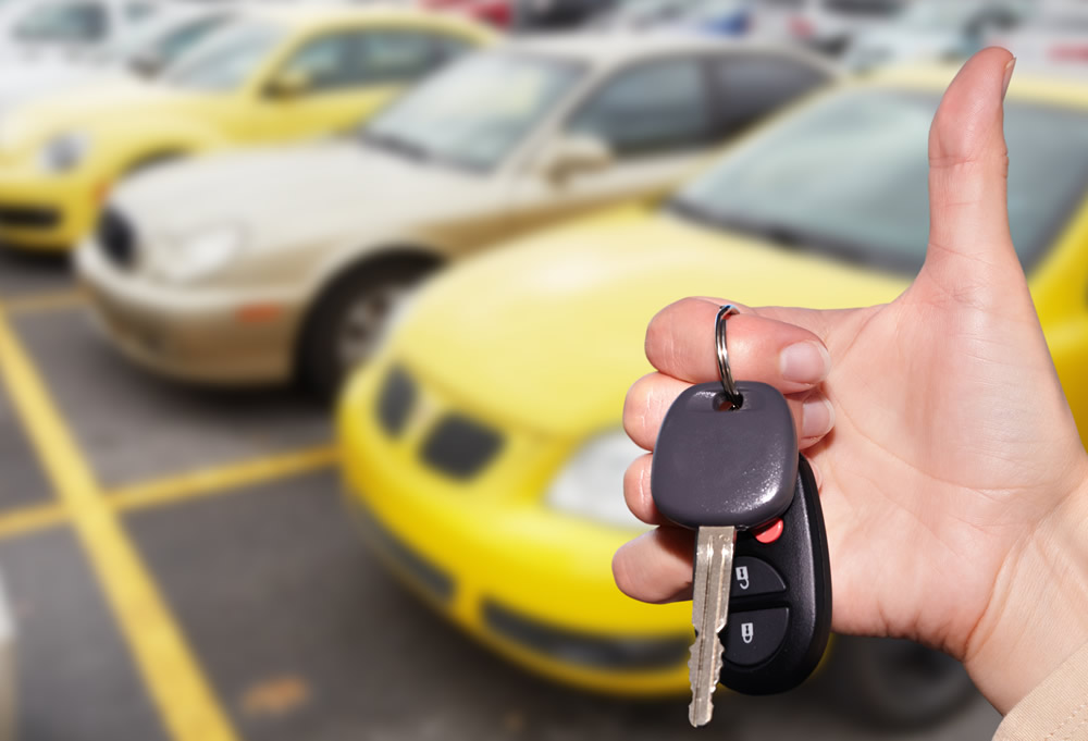 thumbs up with keys in hand in a car lot
