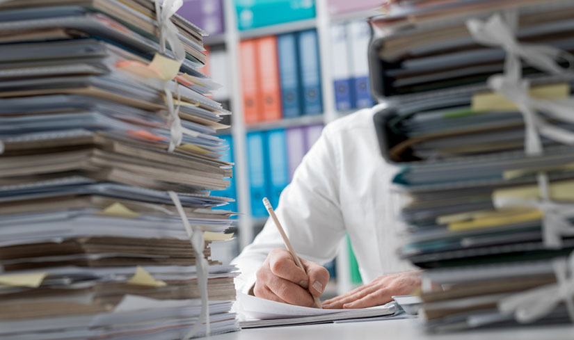 Doctor completing stacks of paperwork