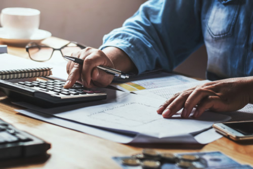 man working at desk with calculator and papers